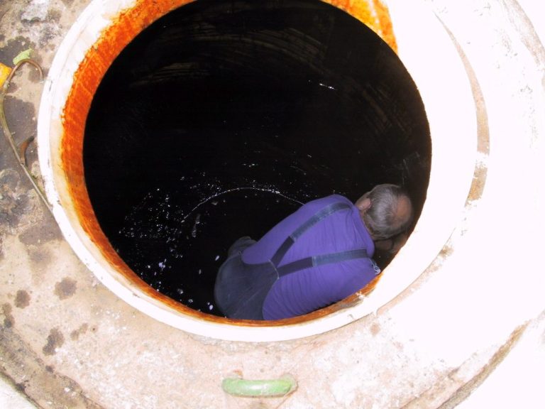 Mann sitzt in einem Tank und führt eine Tankreinigung durch
