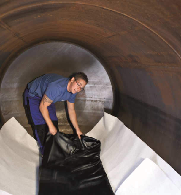 Ein Mann legt eine Tankinnenhülle im Innern eines Tanks aus