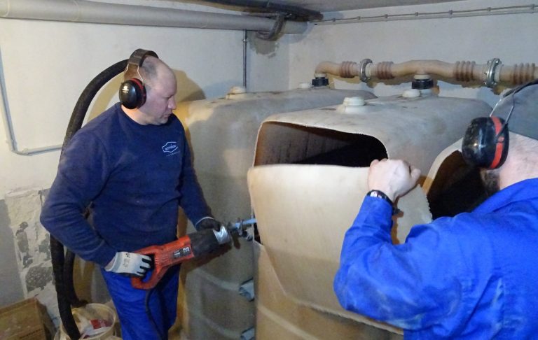 Arbeiter bei der Demontage eines großen Tanks, Geräusche schützend mit Kopfhörern.