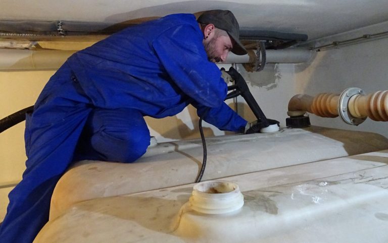 Handwerker in blauer Arbeitskleidung macht eine Tankreinigung