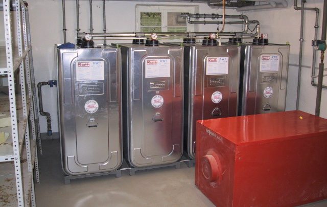 Vier silberne neue Stahlbatterietanks in einem Technikraum.